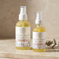 Two bottles of Palmarosa + Bergamot repairing body oil on a wooden surface with a beige background.