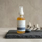 Bottle of 'Muscle + Joint' pain relief oil on a dark surface with a neutral background