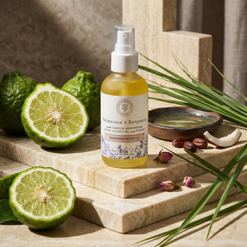 Bottle of repairing body oil with bergamot and leaves on a stone surface. Hello Wellness 