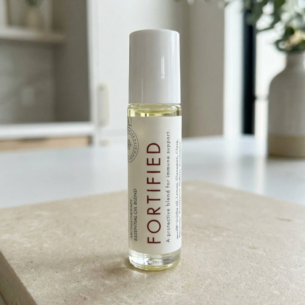Hello Wellness Fortified aromatherapy essential oil roll-on with a white cap and botanical label, displayed on a stone surface.