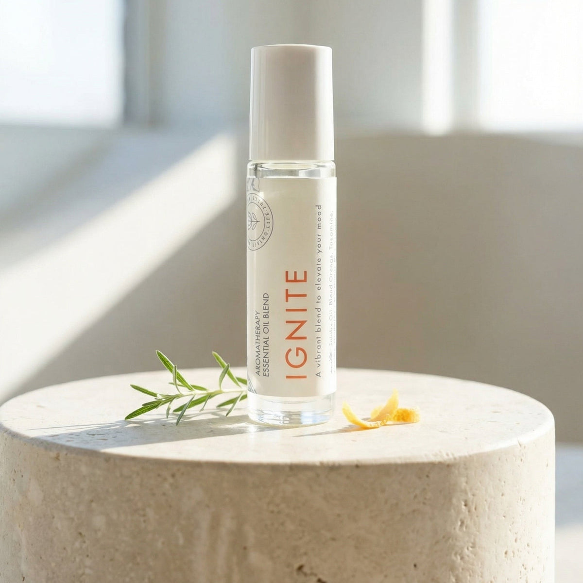 Hello Wellness Ignite aromatherapy essential oil roll-on in a clear glass bottle with a white cap, displayed beside rosemary and citrus peel.
