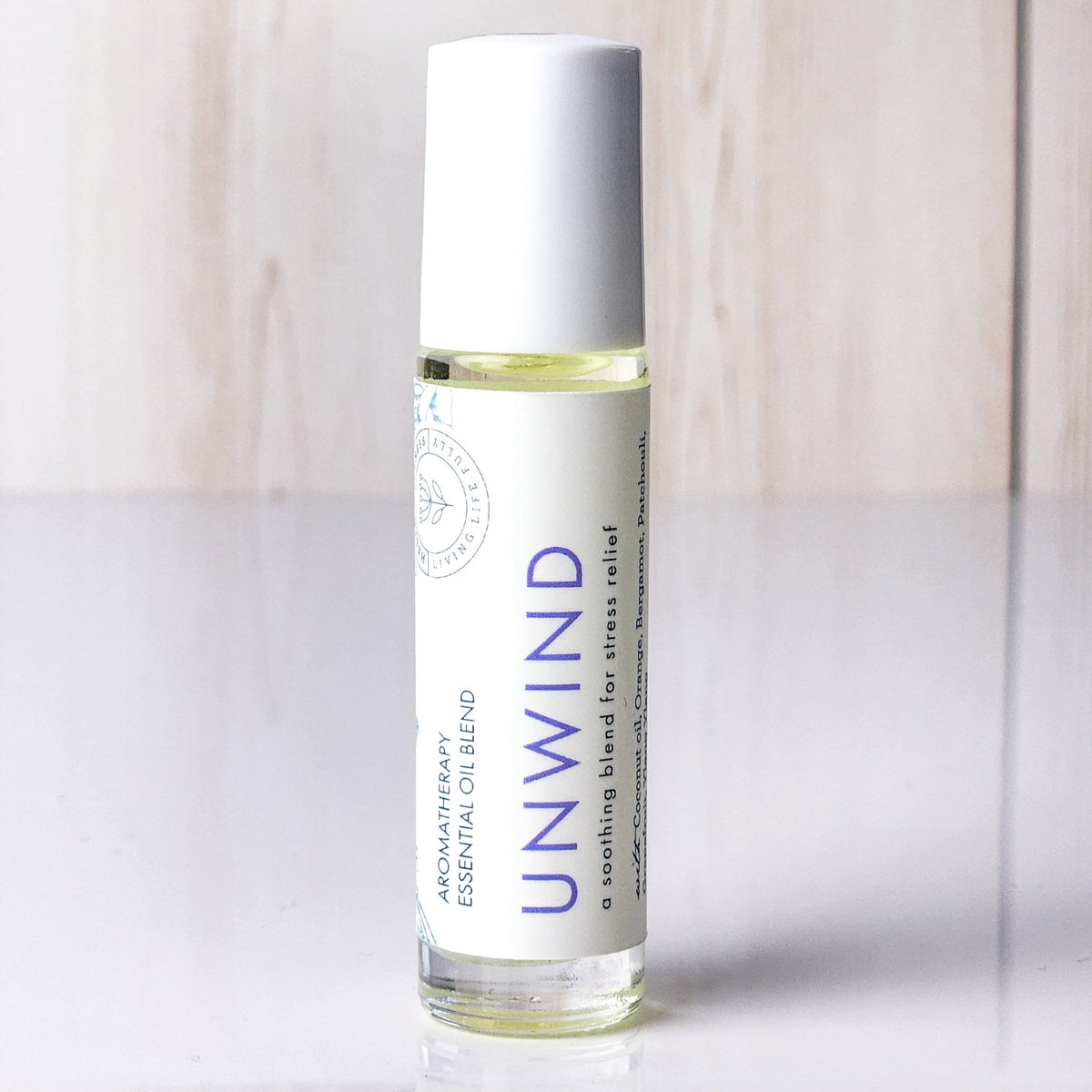 Hello Wellness Unwind aromatherapy essential oil roll-on in a clear glass bottle with a white cap, formulated for stress relief.