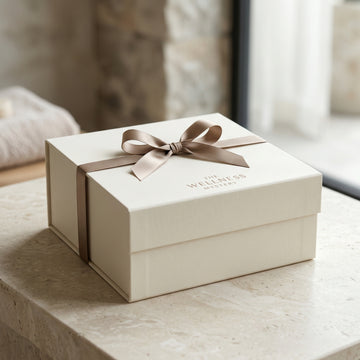 White gift box with a brown ribbon on a light surface