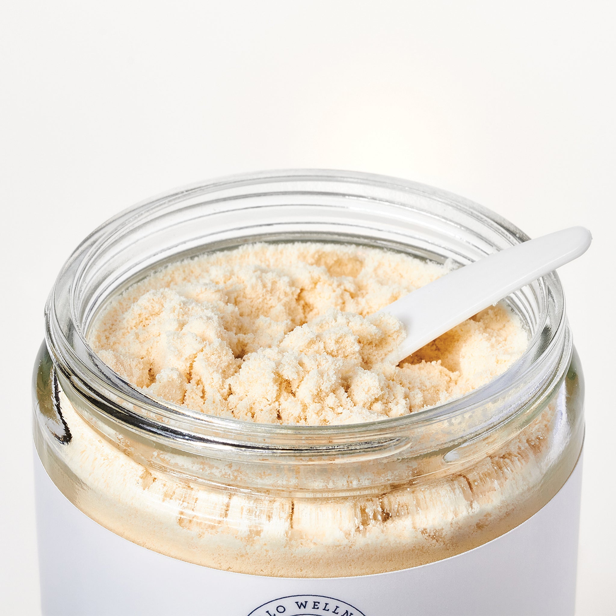An open jar of Coconut Milk Bath Soak by Hello Wellness. Coconut powder to soothe and moisturize dry skin.