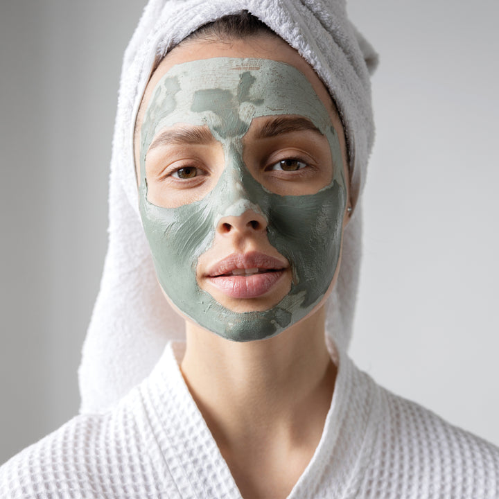 Woman having a facial treatment with the detoxifying green clay face mask on her face. Hello Wellness